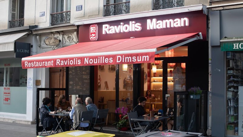Devanture de Raviolis Maman : auvent rouge, enseigne lumineuse blanche et terrasse sur le boulevard Voltaire